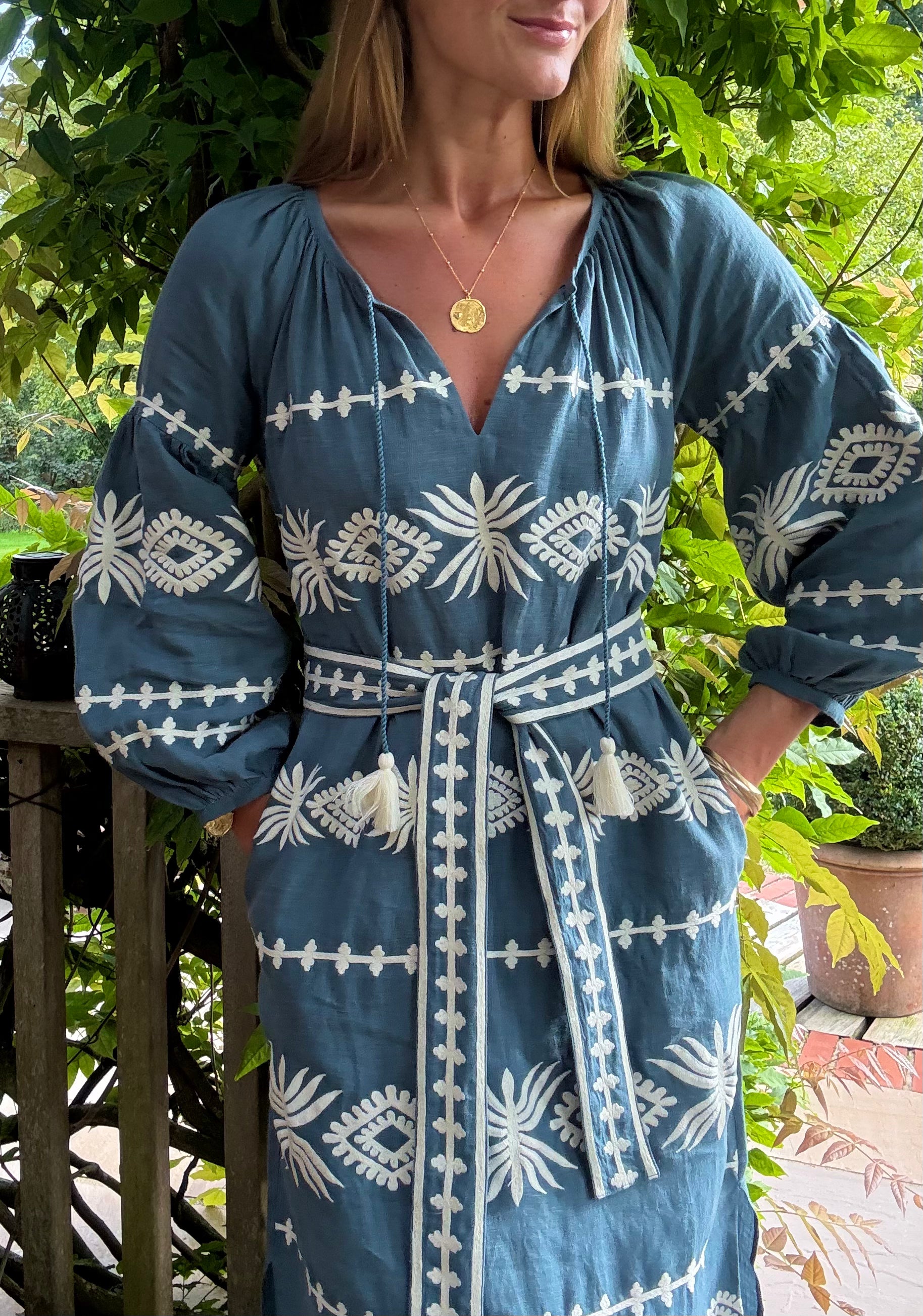 Woman wearing a blue dress with white patterns outdoors.