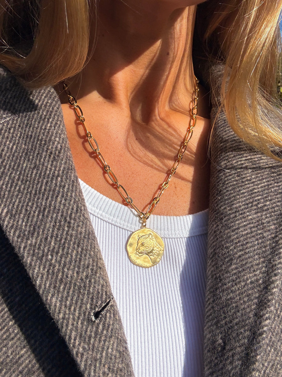 Gold chain necklace with a pendant worn by a person