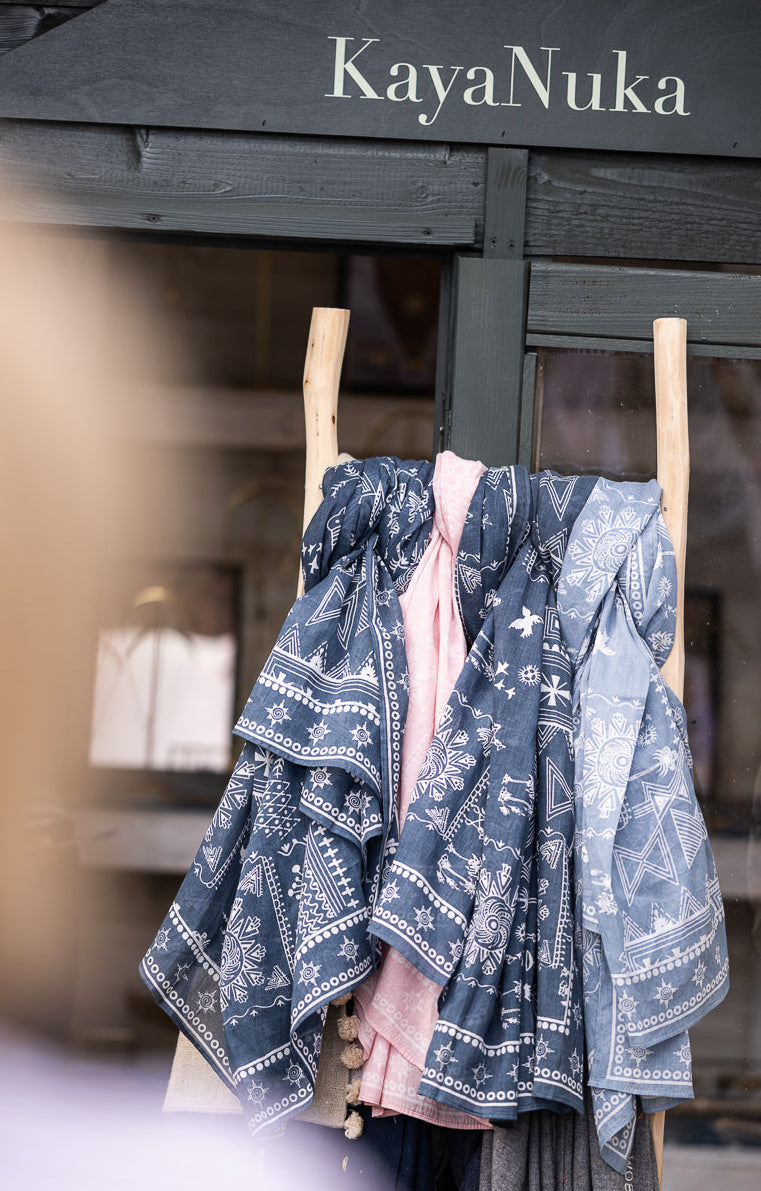Blue patterned dress hanging on a rack under a 'KayaNuka' sign.