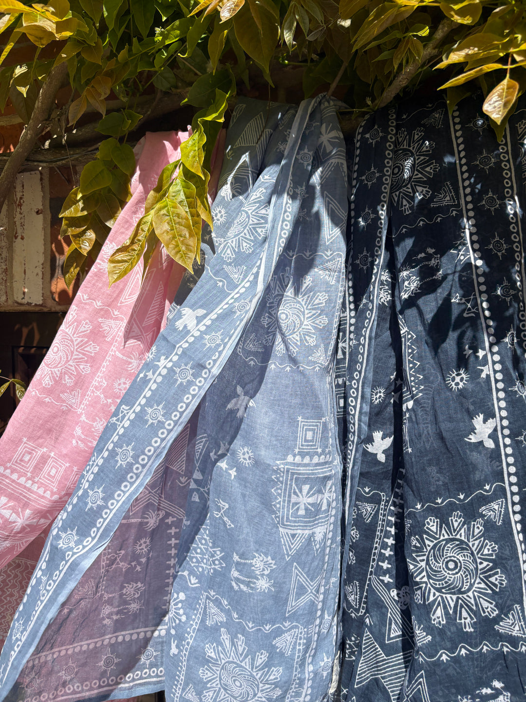 Colorful patterned fabric draped over a surface with green leaves in the background