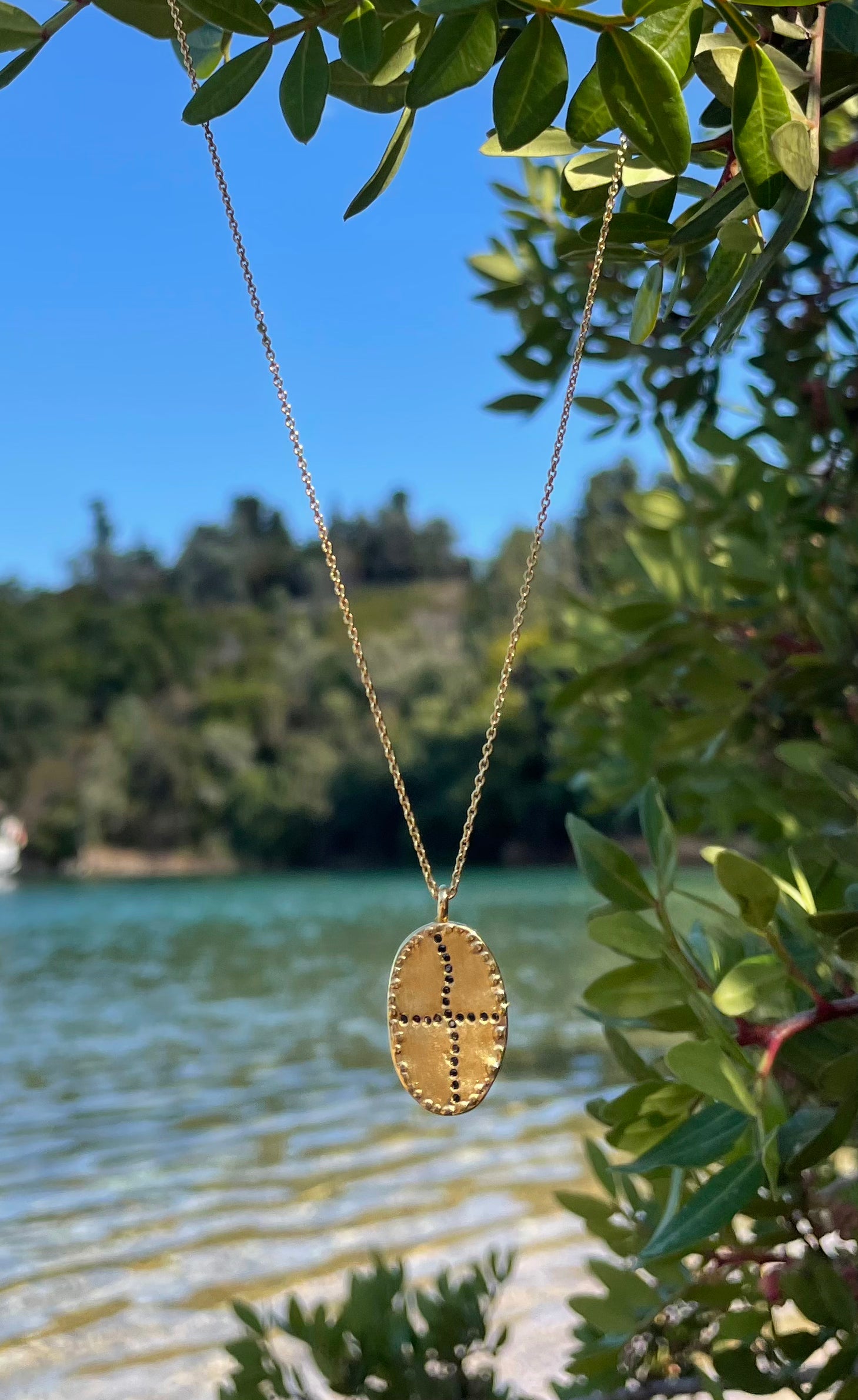 Gold plated short necklace brushed and matte oval black zircons shape of an irregular cross  Louise Hendricks. 